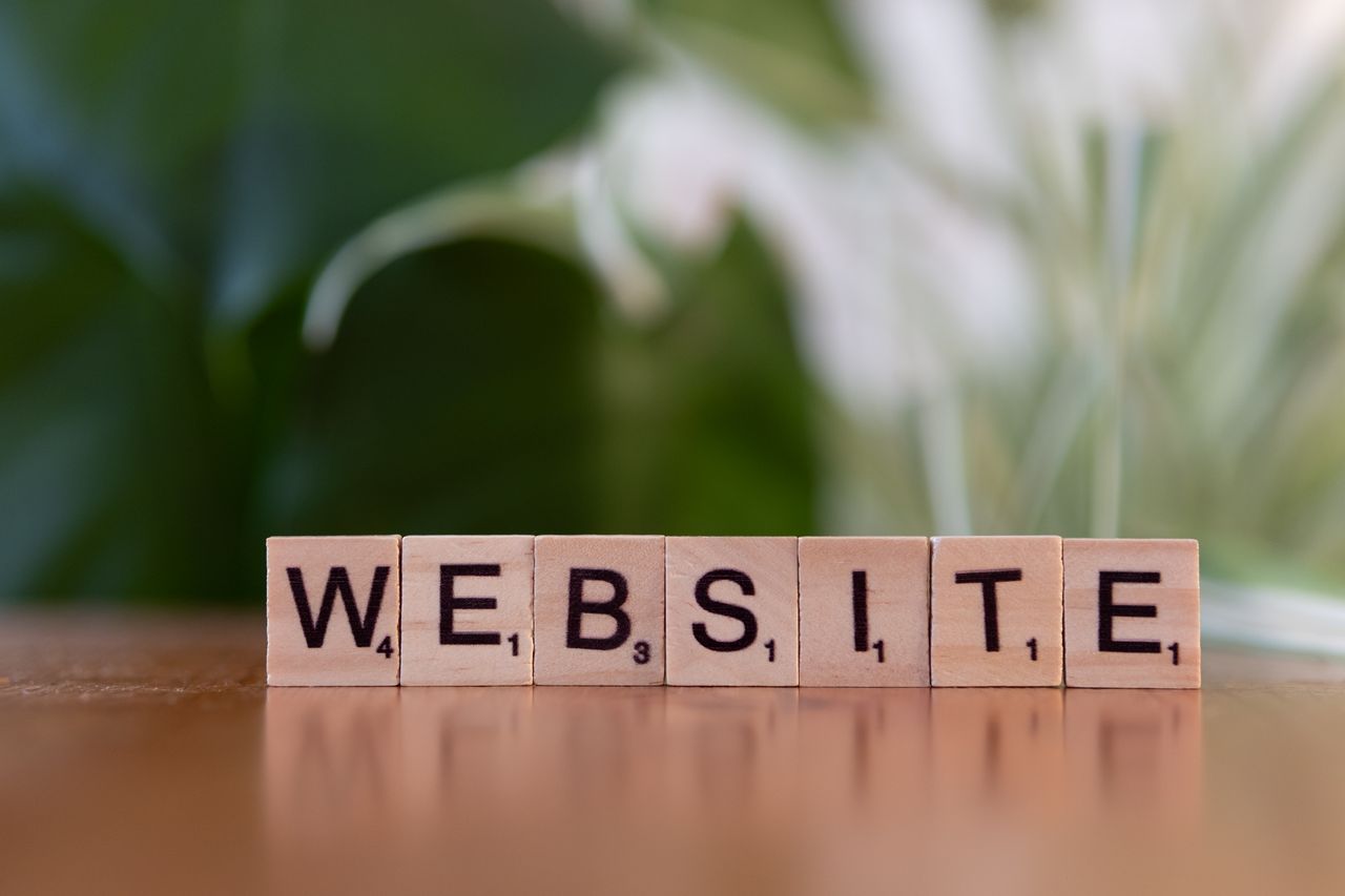 Des lettres de Scrabble posées sur une surface en bois forment le mot Website, symbolisant la communication numérique.